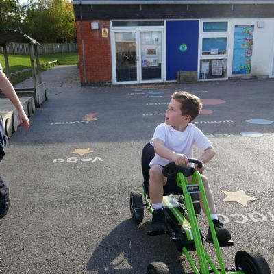 Two pupils talking, one is on a go cart