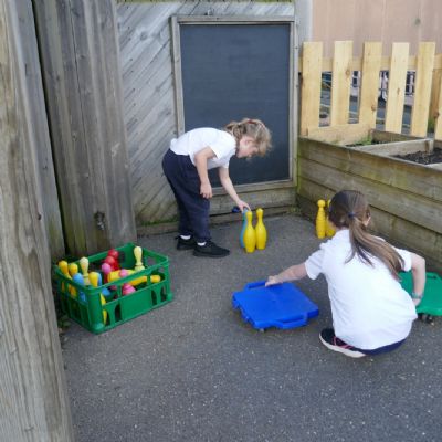 Two pupils setting up a game of skittles