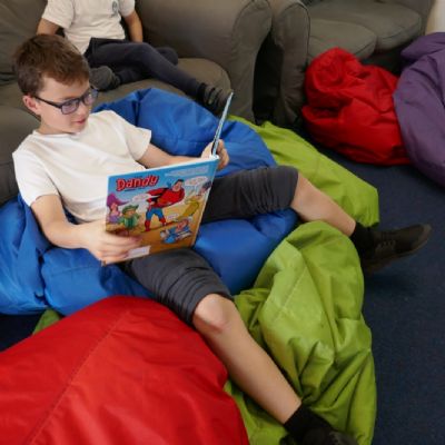 One pupil relaxing with a book on the bean bags